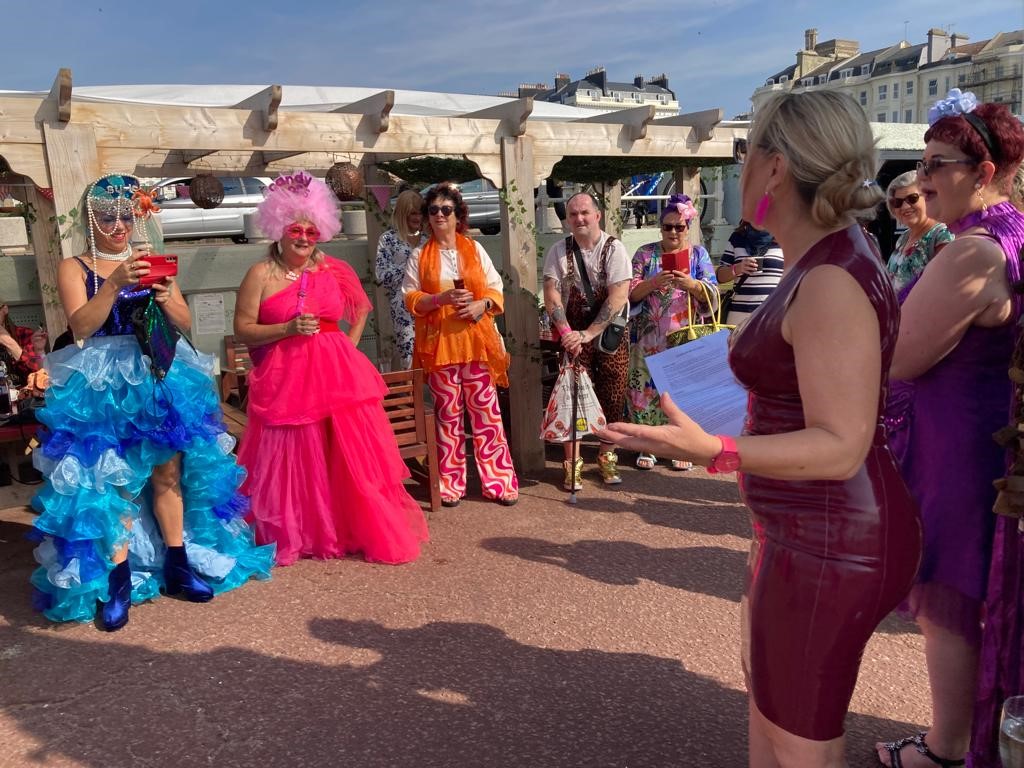 Sarah wearing latex delivering a talk in the morning sunshine to the Frock Up Friday gang in St Leonards